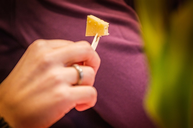 Detailopname van een kaasproeverij bij Zijerveld, waarbij een blokje kaas wordt gepresenteerd op een prikker.